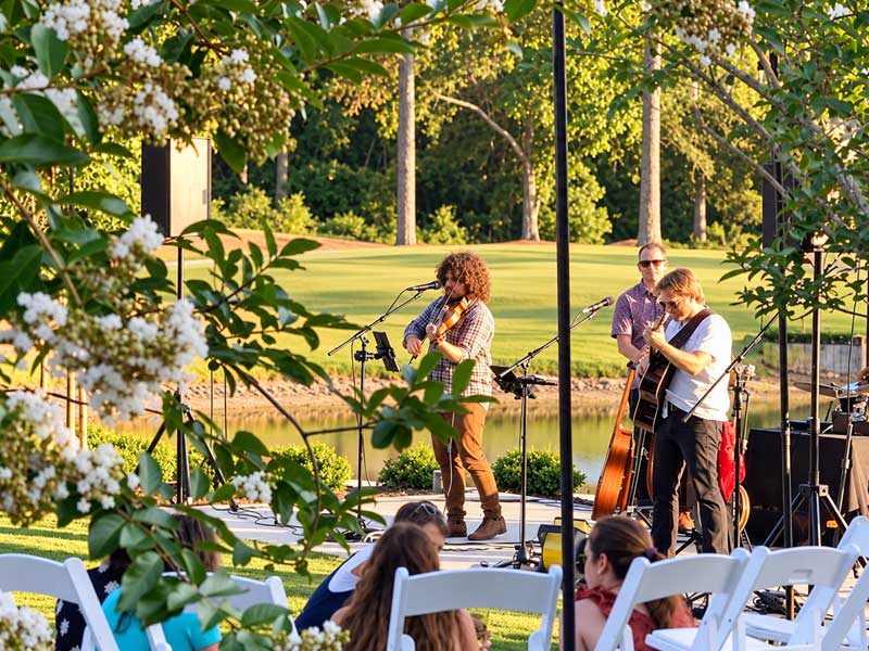 Live musicians performing outdoors at Castle Oaks Golf Club as guests enjoy an event surrounded by trees and landscaped grounds.